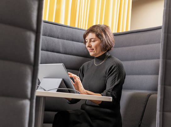 Eine Mitarbeiterin arbeitet mit Engagement am Laptop auf einem bequemen Sessel