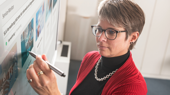 Eine IT-Spezialistin schreibt auf den Bildschirm in einem Meeting