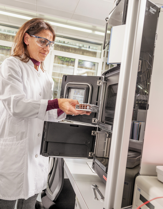 Eine Mitarbeiterin des Gesundheitsamtes entnimmt etwas aus einem Laborschrank