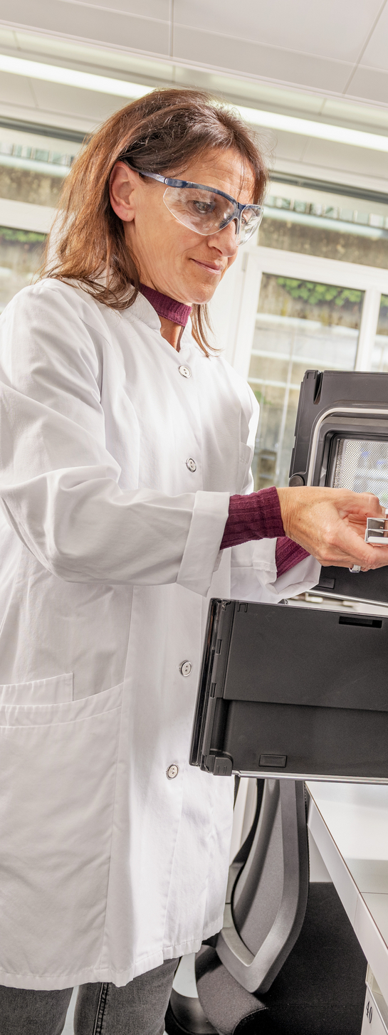 Eine Mitarbeiterin des Gesundheitsamtes entnimmt etwas aus einem Laborschrank