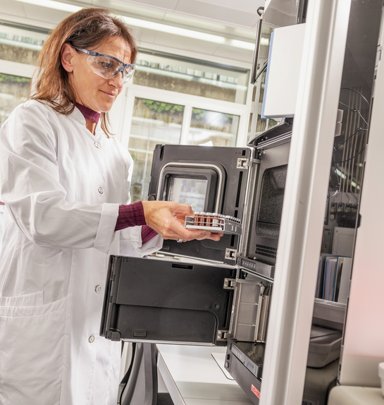 Eine Mitarbeiterin des Gesundheitsamtes entnimmt etwas aus einem Laborschrank