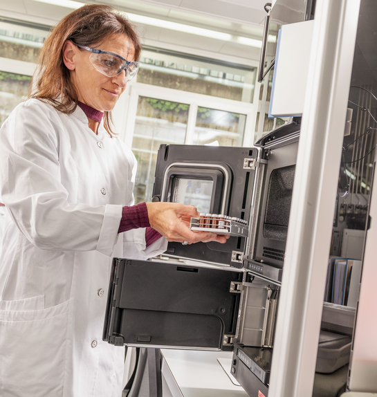 Eine Mitarbeiterin des Gesundheitsamtes entnimmt etwas aus einem Laborschrank