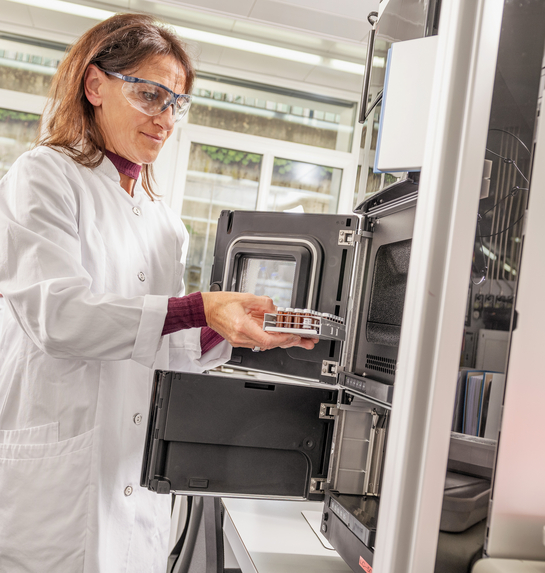 Eine Mitarbeiterin des Gesundheitsamtes entnimmt etwas aus einem Laborschrank