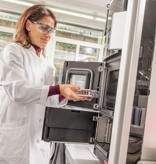 Eine Mitarbeiterin des Gesundheitsamtes entnimmt etwas aus einem Laborschrank