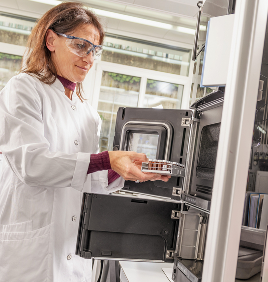 Eine Mitarbeiterin des Gesundheitsamtes entnimmt etwas aus einem Laborschrank