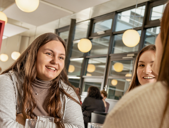 junge Arbeitskollegen unterhalten sich fröhlich in der Kantine