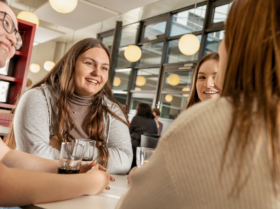 junge Arbeitskollegen unterhalten sich fröhlich in der Kantine