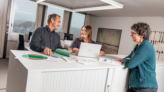 Drei Mitarbeitende aus dem Amt für Kultur und Sport haben ein Meeting an einem Stehpult