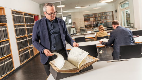 Ein Mitarbeiter des Staatsarchiv blättert in einem alten Buch