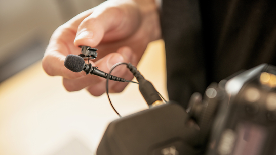 Eine Hand steckt ein Kabel in eine professionelle Kamera