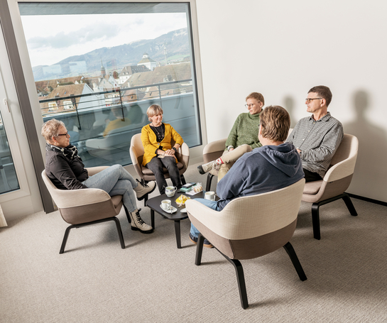 eine Gruppe von Arbeitskollegen unterhalten sich während der Pause in lockerer Umgebung