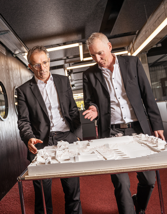 Zwei Mitarbeitende des Hochbauamts unterhalten sich über ein Gebäudemodell