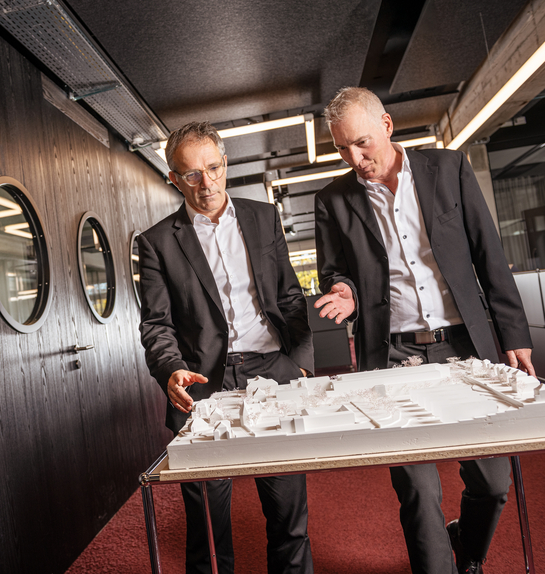 Zwei Mitarbeitende des Hochbauamts unterhalten sich über ein Gebäudemodell