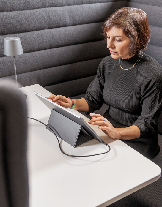 Eine Mitarbeiterin arbeitet mit Engagement am Laptop auf einem bequemen Sessel