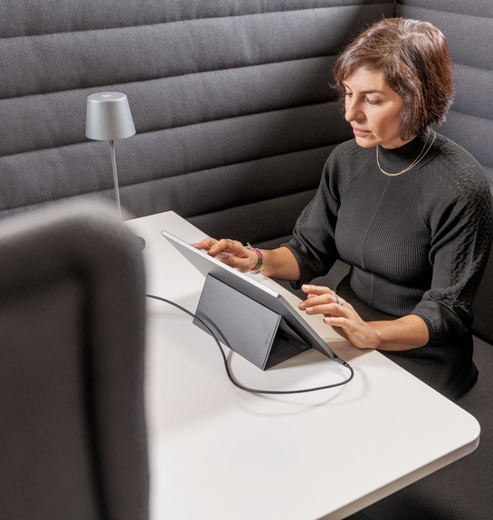 Eine Mitarbeiterin arbeitet mit Engagement am Laptop auf einem bequemen Sessel