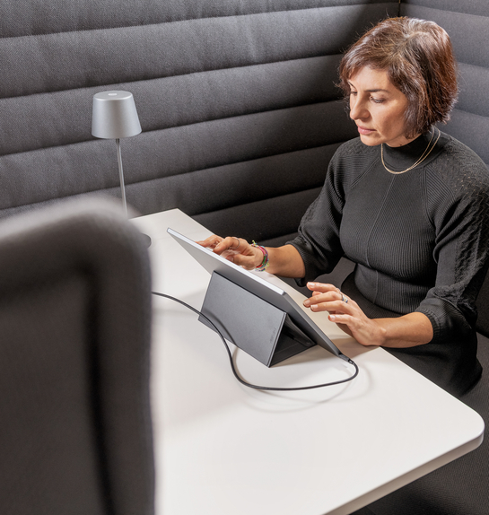 Eine Mitarbeiterin arbeitet mit Engagement am Laptop auf einem bequemen Sessel