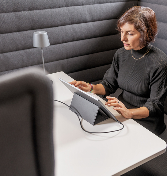 Eine Mitarbeiterin arbeitet mit Engagement am Laptop auf einem bequemen Sessel