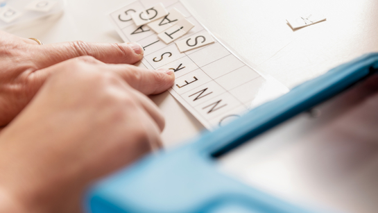 Hände, die verschiedene Buchstaben aneinander reihen