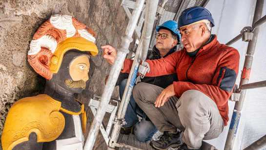 Zwei Männer aus dem Amt für Denkmalpflege und Archäologie stehen auf einem Gerüst und besprechen die Restauration einer Statue