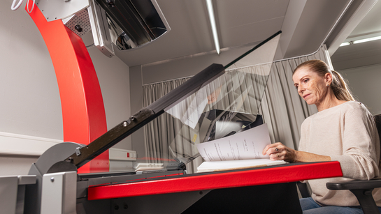 Eine Mitarbeiterin aus dem Staatsarchiv scannt die Seiten eines Buches an einem grossen Scanner ein