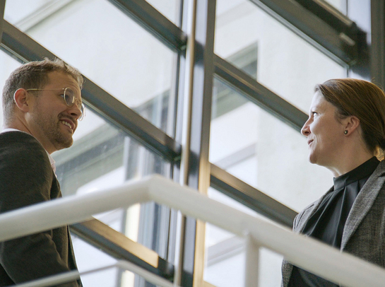 Ein Mann und eine Frau unterhalten sich im Treppenhaus.