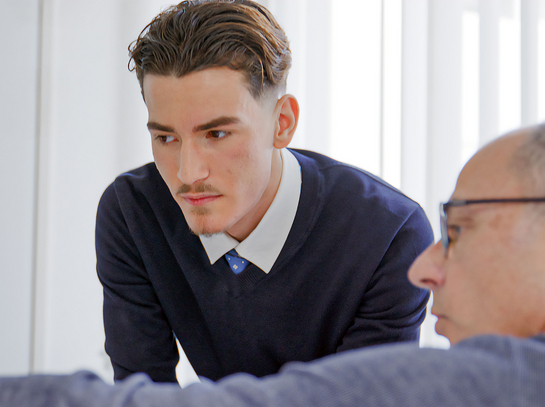 Ein Mitarbeiter aus dem Steueramt erklärt dem Lernenden etwas am Bildschirm