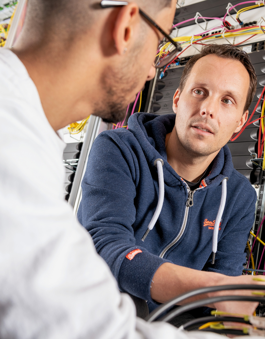 Zwei Informatiker schauen sich eine Hardware an im Serverraum