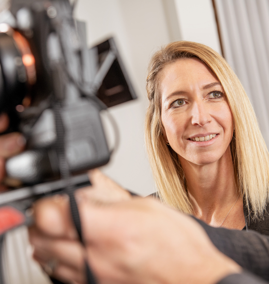 Eine Mitarbeiterin lernt die technischen Einstellungen einer professionellen Kamera