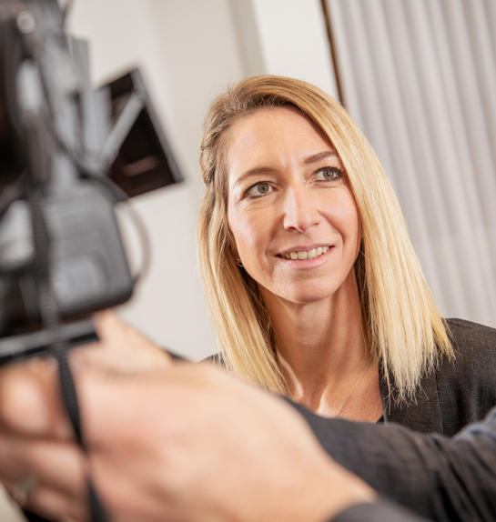 Eine Mitarbeiterin lernt die technischen Einstellungen einer professionellen Kamera