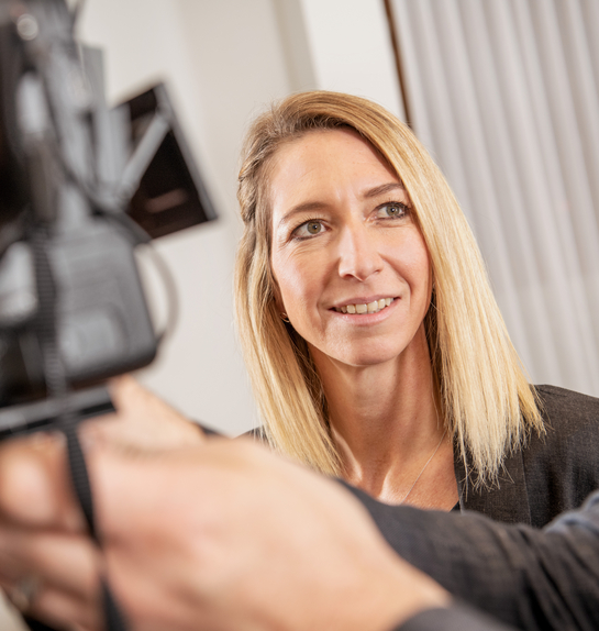 Eine Mitarbeiterin lernt die technischen Einstellungen einer professionellen Kamera