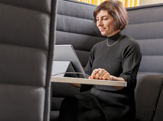 Eine Mitarbeiterin arbeitet mit Engagement am Laptop auf einem bequemen Sessel