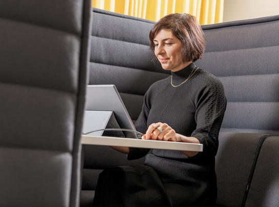 Eine Mitarbeiterin arbeitet mit Engagement am Laptop auf einem bequemen Sessel