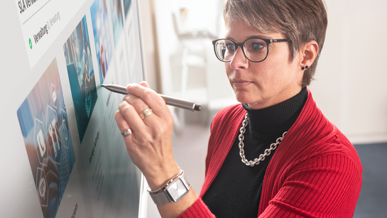 Eine IT-Spezialistin schreibt auf den Bildschirm in einem Meeting