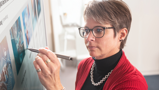 Eine IT-Spezialistin schreibt auf den Bildschirm in einem Meeting