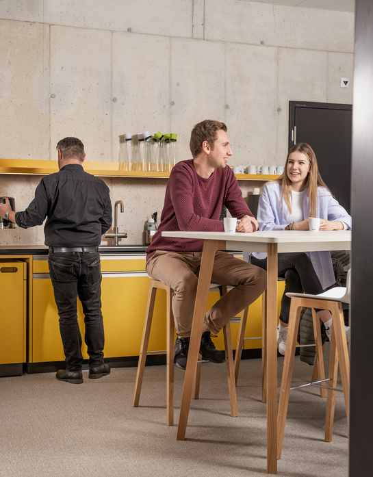 Zwei junge Mitarbeitende beim Gespräch während der Pause in der Cafeteria