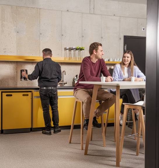 Zwei junge Mitarbeitende beim Gespräch während der Pause in der Cafeteria