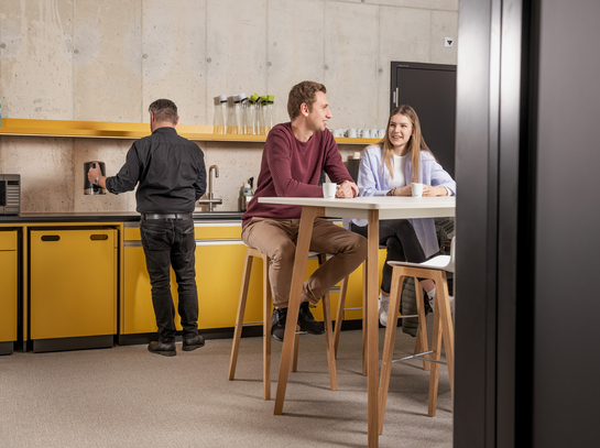 Zwei junge Mitarbeitende beim Gespräch während der Pause in der Cafeteria