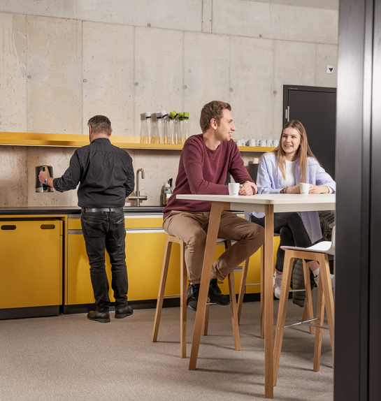 Zwei junge Mitarbeitende beim Gespräch während der Pause in der Cafeteria