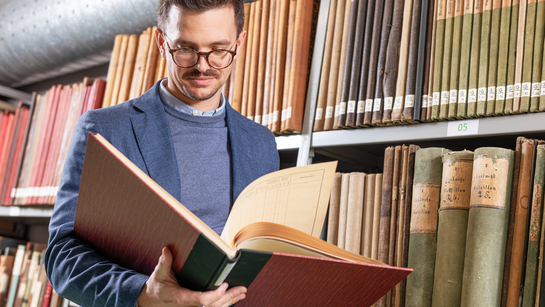 Ein Mitarbeiter des Staatsarchiv blättert in einem alten Buch
